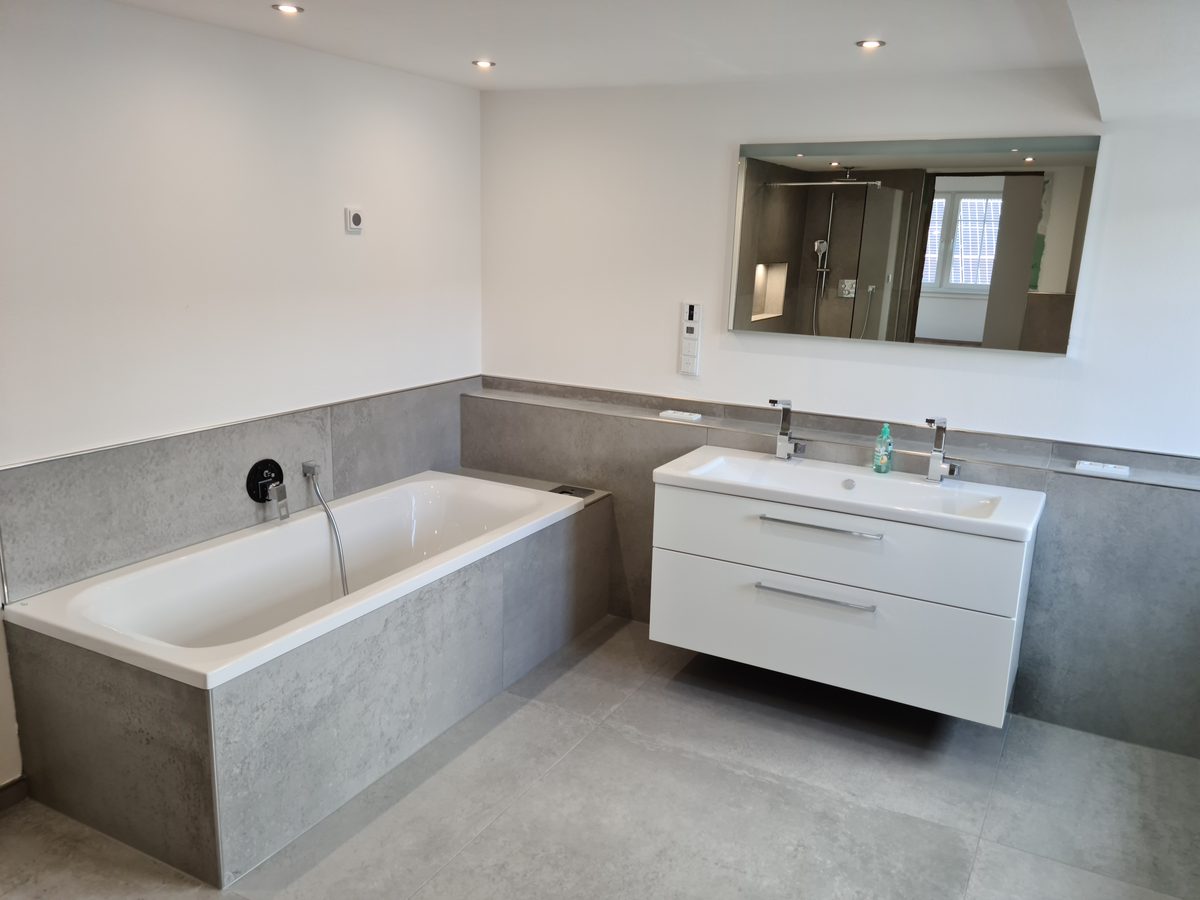 Badezimmer mit Badewanne, Doppelwaschtisch und großformatigen Fliesen